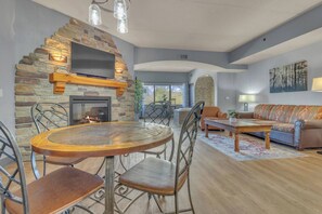 A living room with a stone fireplace, a round dining table, and a sofa. - High Tides - Sleeps 14 | Video Games (Wisconsin Dells)