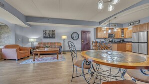 A modern kitchen with stainless steel appliances, a dining area with a round table, and a living room with a sofa and a coffee table. - High Tides - Sleeps 14 | Video Games (Wisconsin Dells)