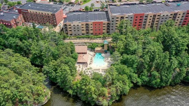 A hotel with a swimming pool surrounded by dense greenery. - High Tides - Sleeps 14 | Video Games (Wisconsin Dells)