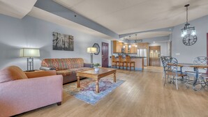 A living room with a sofa, coffee table, and dining area with chairs. - High Tides - Sleeps 14 | Video Games (Wisconsin Dells)