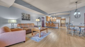 A living room with a sofa, coffee table, and dining area with chairs. - High Tides – Spacious Condo Sleeps 14 with Video Games (Wisconsin Dells)