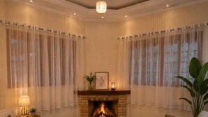 Een woonkamer met een open haard, twee banken, een salontafel en een lamp.
