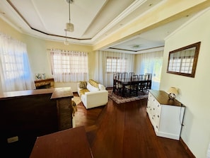 A spacious living area with a dining table, sofa, and wooden flooring.
