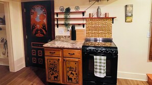 A kitchen with wooden cabinets, a stove, and a decorative ceiling mural.