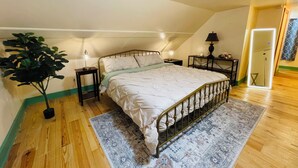 A bedroom with a bed, bedside tables, a lamp, a potted plant, and a patterned rug.