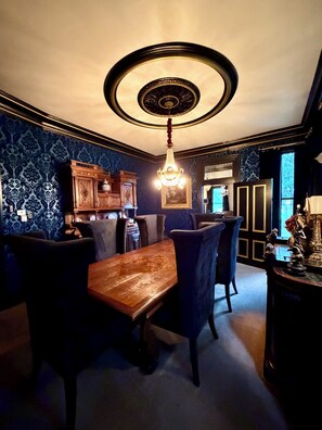 A dining area with a wooden table and chairs, a chandelier, and patterned wallpaper. - "THE MAYBELLE" 1892 Historic Two Story Victorian Home, Downtown Springfield, TN (Springfield)