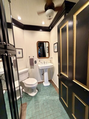 A bathroom with a toilet, sink, mirror, and a door with gold trim. - "THE MAYBELLE" 1892 Historic Two Story Victorian Home, Downtown Springfield, TN (Springfield)