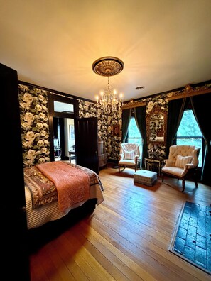 A room with a bed, two chairs, a chandelier, and a stone wall. - "THE MAYBELLE" 1892 Historic Two Story Victorian Home, Downtown Springfield, TN (Springfield)