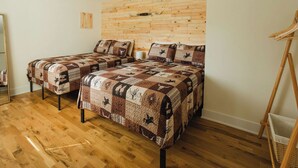 Habitación con dos camas, piso de madera, cabecera de madera y un caballete de madera.