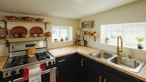 Una cocina con estufa a gas, horno, dos fregaderos y una ventana con vistas.