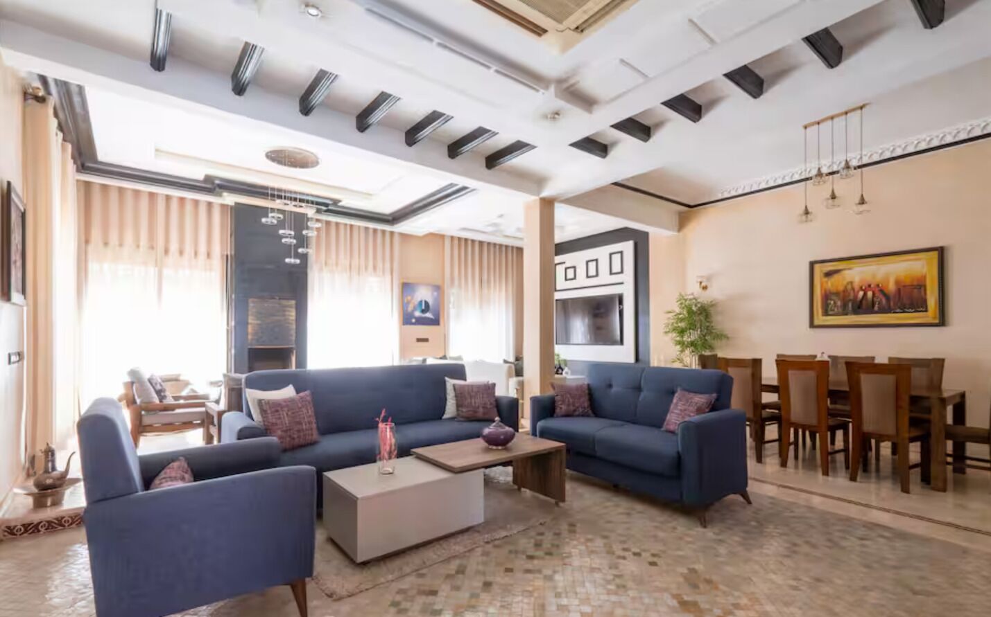 A modern living room with sofas, a coffee table, and a dining area with wooden chairs and a table.