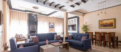 A modern living room with sofas, a coffee table, and a dining area with wooden chairs and a table.