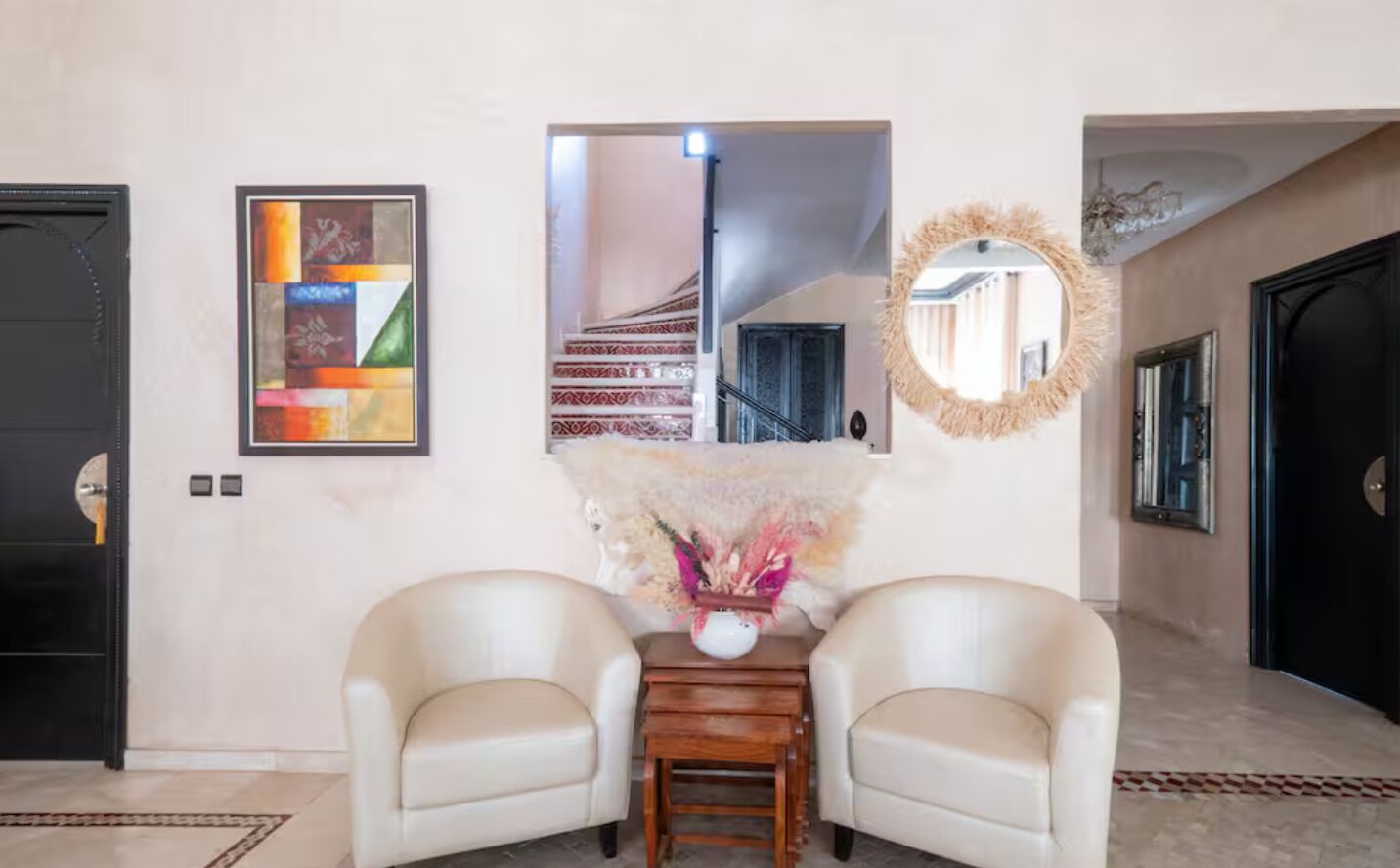 A hallway with two chairs, a mirror, and artwork on the walls.