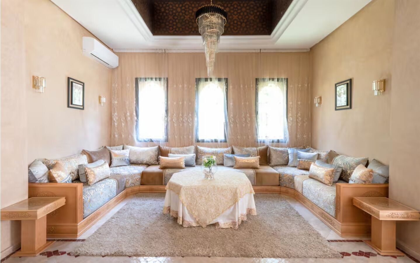 A spacious living room with a large L-shaped sofa, a round coffee table, and a chandelier.