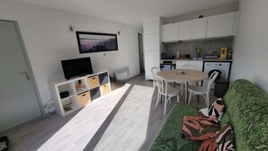 A compact living space with a dining area, kitchenette, and a television mounted on the wall. - 247 - Your stay facing Hourtin Port – Superb view and peaceful setting (HOURTIN)