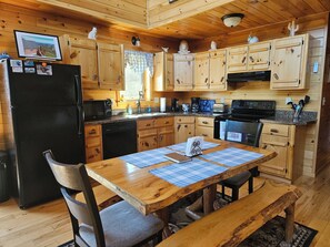 Une cuisine de style rustique, avec des éléments en bois, comprenant un réfrigérateur, un four à micro-ondes, une cuisinière et des placards en bois.