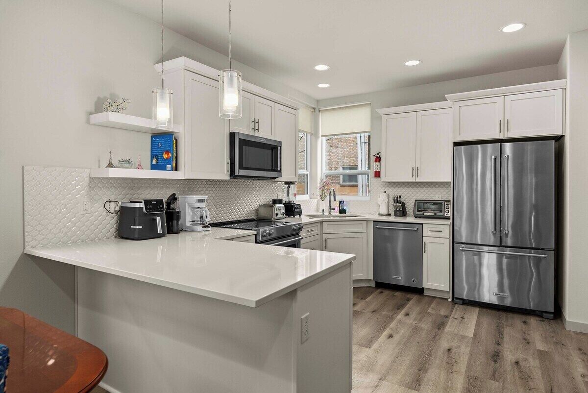 A modern kitchen with white cabinetry, stainless steel appliances, and a central island.