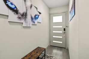 A hallway with a bench, a door with frosted glass panels, and artwork on the walls. - Sleek 3BR Seattle Townhome - Near UW-Husky Stadium (Seattle)