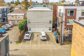 A parking lot with several cars, a building with a flat roof, and adjacent residential buildings. - Sleek 3BR Seattle Townhome - Near UW-Husky Stadium (Seattle)