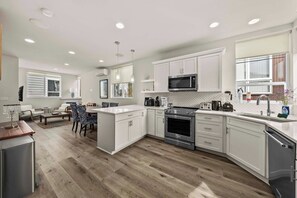 A modern kitchen with white cabinets, stainless steel appliances, and a wooden floor. - Sleek 3BR Seattle Townhome - Near UW-Husky Stadium (Seattle)