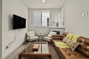 A living room with a flat-screen TV, a fireplace, a sofa, and two armchairs. - Sleek 3BR Seattle Townhome - Near UW-Husky Stadium (Seattle)