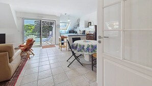 Ein kompakter Wohnraum mit Essbereich, Küchenzeile und einer Glastür zum Balkon.