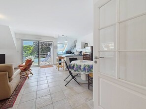 A compact living space with a dining area, kitchenette, and a sliding glass door leading to a balcony. - Carnac – 3-room apartment – 65m² – Wi-Fi (CARNAC)