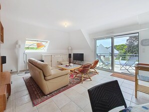A modern living room with a sofa, chairs, a TV, and a dining area. - Carnac – 3-room apartment – 65m² – Wi-Fi (CARNAC)