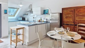 Eine moderne Küche mit weißen Schränken, einem eingebauten Backofen und einem Essbereich mit rundem Tisch für vier Personen.