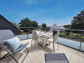 A balcony with a table set for two, a chair, and a sofa with a cushion. - Carnac – 3-room apartment – 65m² – Wi-Fi (CARNAC)