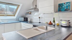 Eine moderne Küche mit Dachfenster, weißen Schränken, einem Einbauofen und einem Toaster.