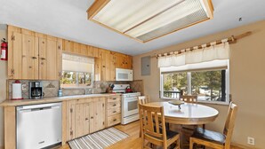 A kitchen with wooden cabinets, a microwave, a dishwasher, a stove, and a dining table with chairs. - 68tlf2 (Frisco)