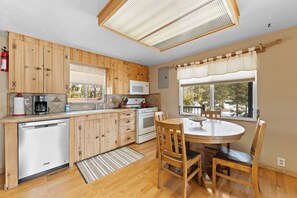 A kitchen with wooden cabinets, a microwave, a dishwasher, a stove, and a dining table with chairs. - 68tlf2 (Frisco)