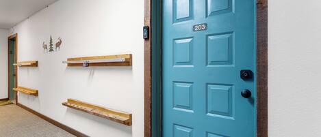 A hallway with a teal door marked 203, wooden shelves, and a carpeted floor.