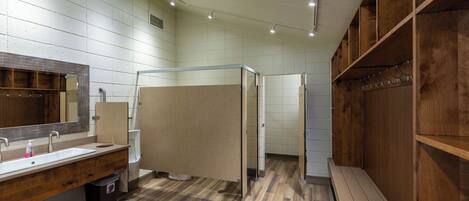 Un baño moderno con tocador de madera, un espejo grande y zona de ducha.