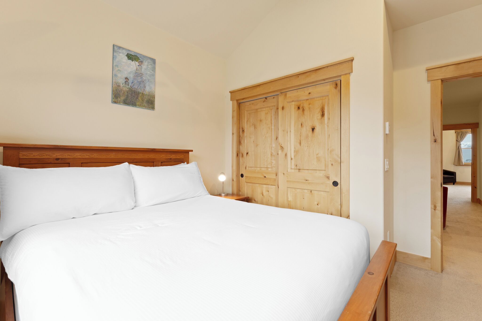 Un dormitorio con una cama grande, un armario de madera y un cuadro en la pared.