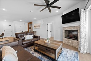 Ein modernes Wohnzimmer mit Kamin, Ledersofa und Flachbildfernseher.