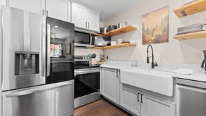 A modern kitchen with stainless steel appliances, wooden shelves, and a painting on the wall. - 204efc-2 (Silverthorne)