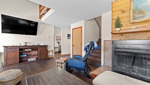 A living room with a fireplace, a television, and a staircase. - 204efc-2 (Silverthorne)