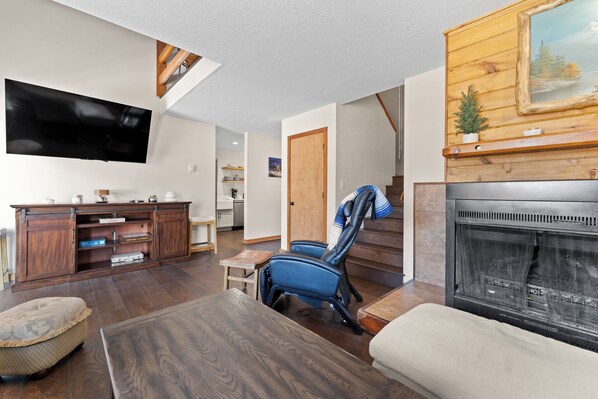 A living room with a fireplace, a television, and a staircase. - 204efc-2 (Silverthorne)