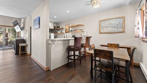 A modern kitchen with a dining area, wooden flooring, and a view of the outdoors. - 204efc-2 (Silverthorne)