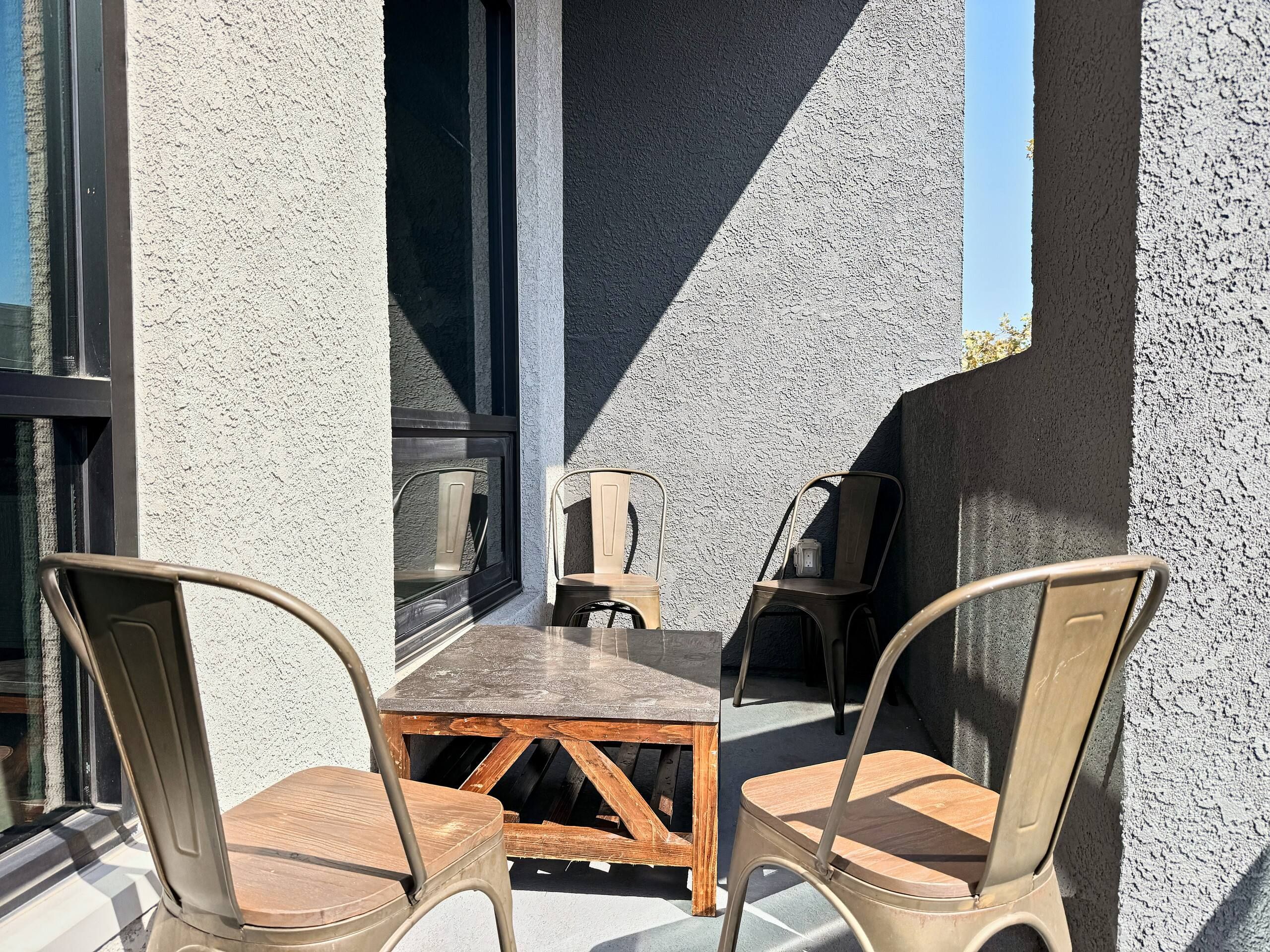 Un espace extérieur aménagé avec une table et des chaises, une fenêtre et un mur à texture.