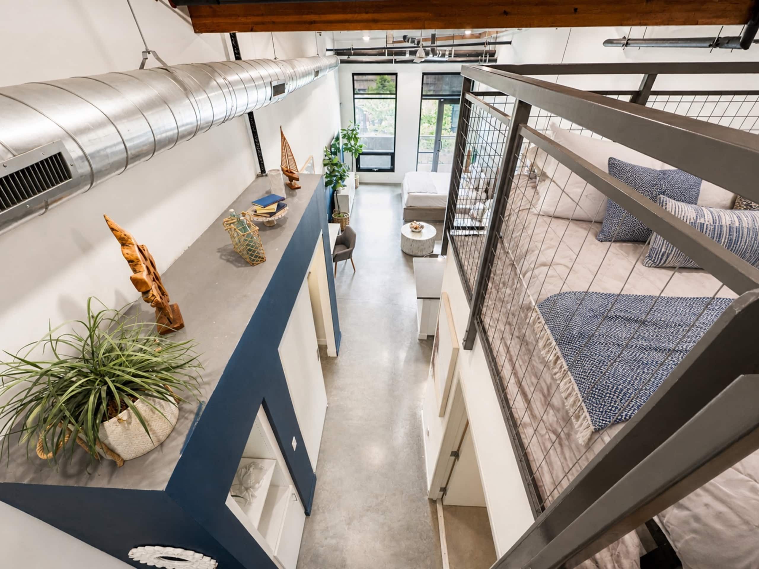 A modern interior with a mezzanine level, a staircase, and a view of the outdoors.