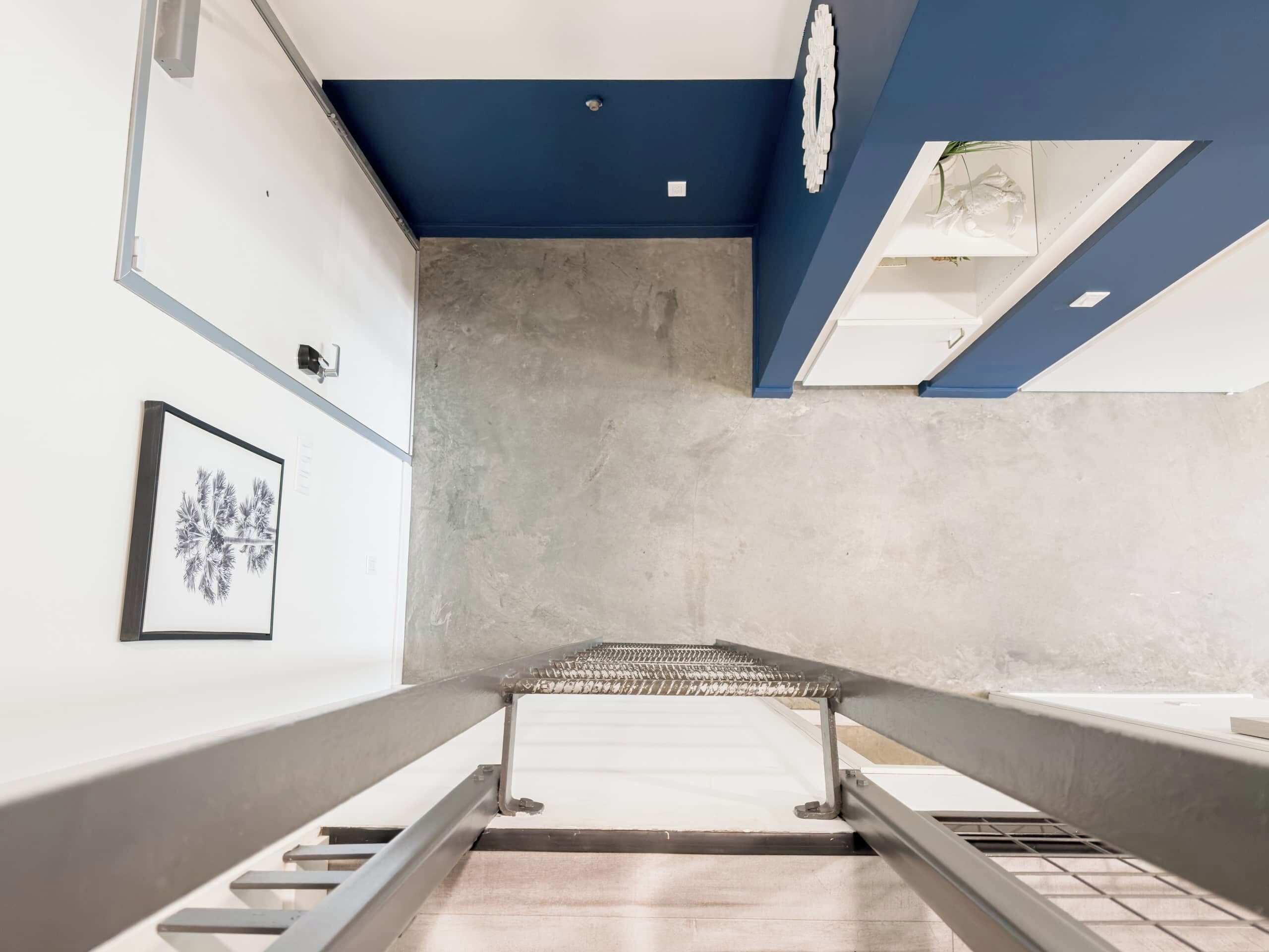 A staircase with metal railings, a concrete wall, and a framed picture on the left.