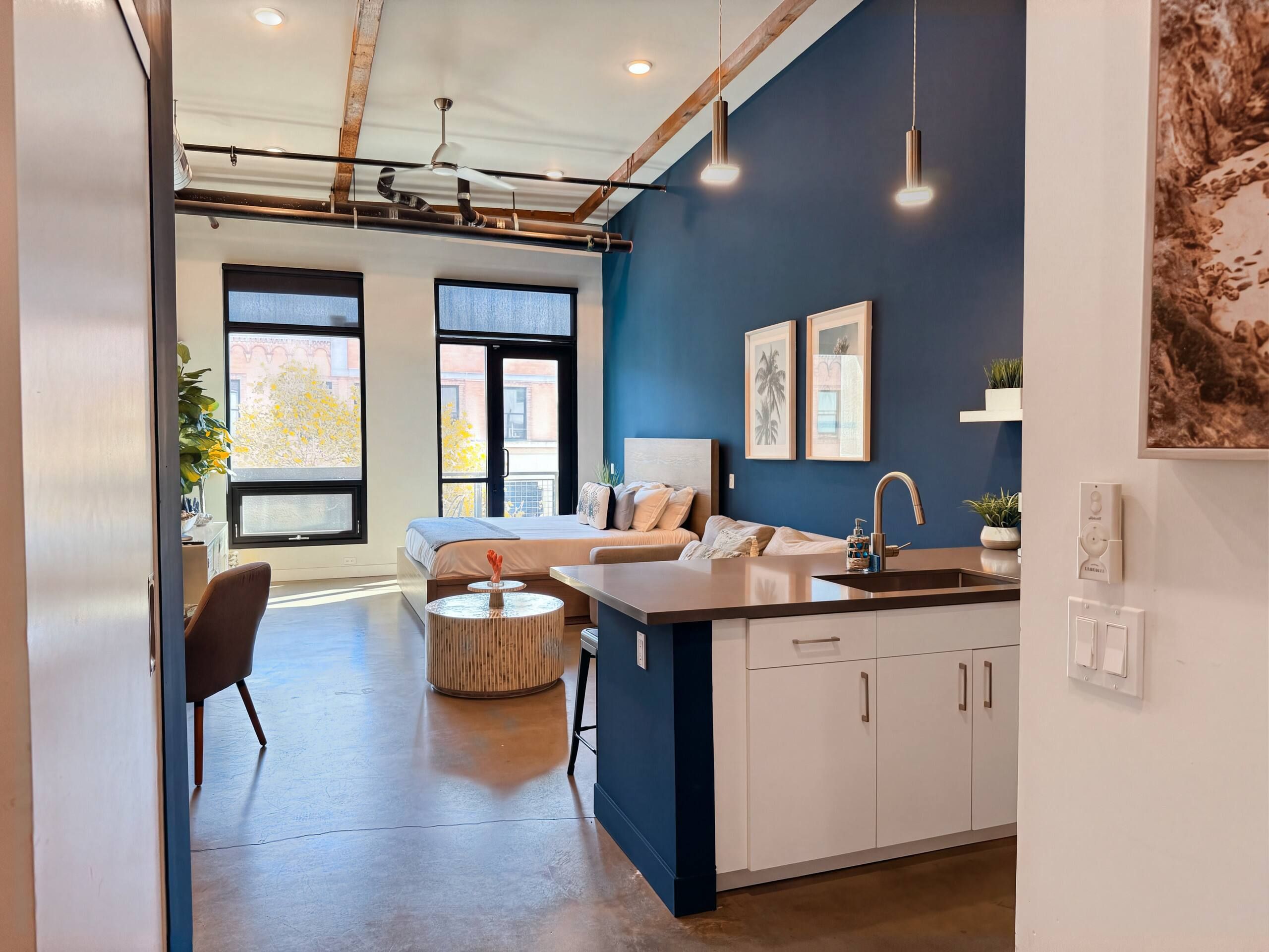 A modern apartment with a kitchen, dining area, and a bedroom with a large window.