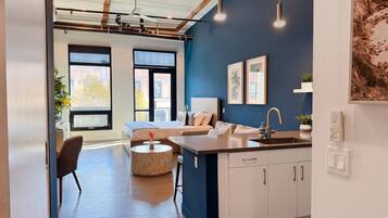 A modern apartment with a kitchen, dining area, and a bedroom with a large window.