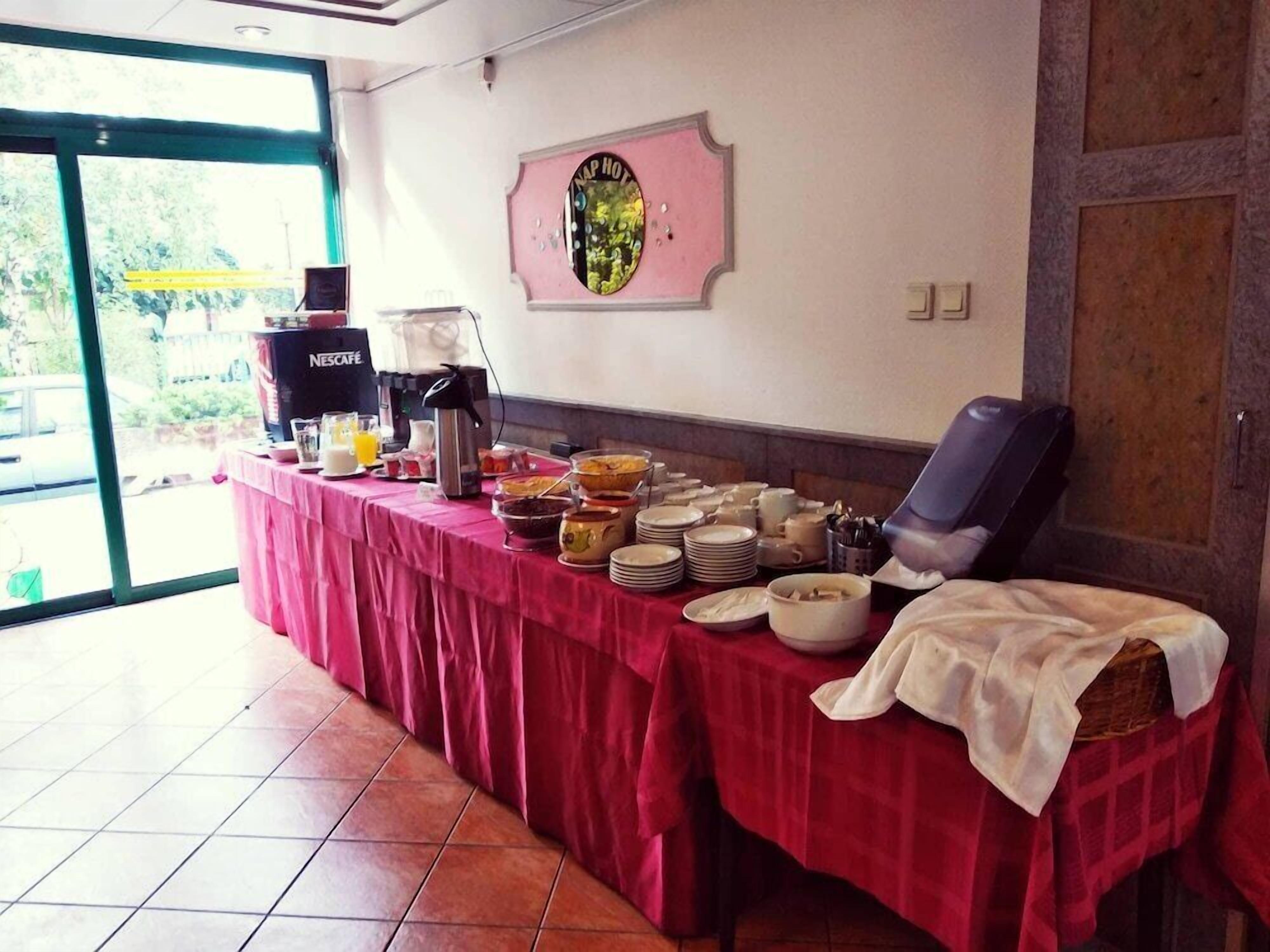 Une table de buffet avec divers plats et une machine à café, un fauteuil de massage et un panneau fixé au mur.