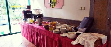 Une table de buffet avec divers plats et une machine à café, un fauteuil de massage et un panneau fixé au mur.