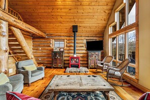 A log cabin interior with a fireplace, wooden walls, a television, and seating. - Emerald Lookout - Views, Hot Tub, Trails Right Next Door (Steamboat Springs)