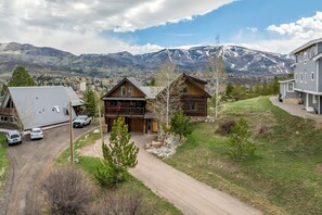 A lodge with a wooden exterior, a dirt driveway, and a mountain backdrop. - Emerald Lookout - Views, Hot Tub, Trails Right Next Door (Steamboat Springs)